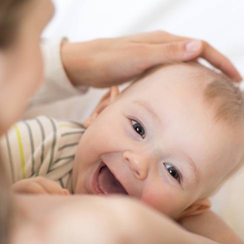 Laughing baby enjoying benefits and results of frenectomy