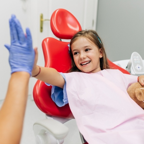 Child giving dentist a high five after lip and Tongue-Tie treatment