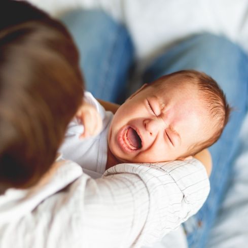 Parent holding crying baby with Tongue-Tie