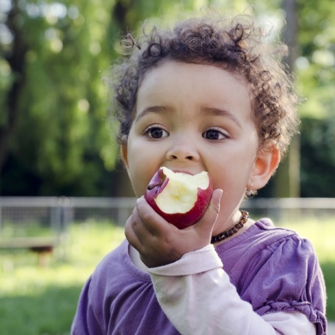 Young child eating an apple thanks to Tongue-Tie treatment