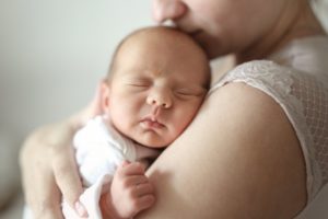 mom watching over her sleeping newborn with a lip or tongue tie