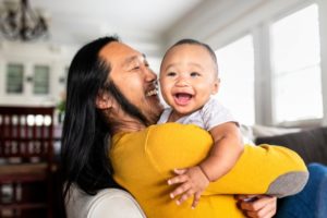 a parent holding a laughing child while sitting on a couch