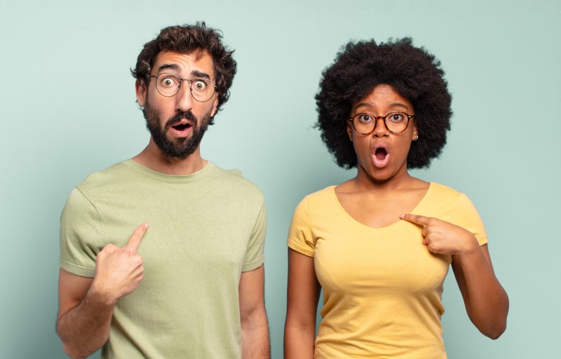 a man and woman surprised and pointing at themselves