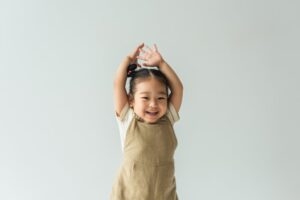 a toddler laughing with her hands up