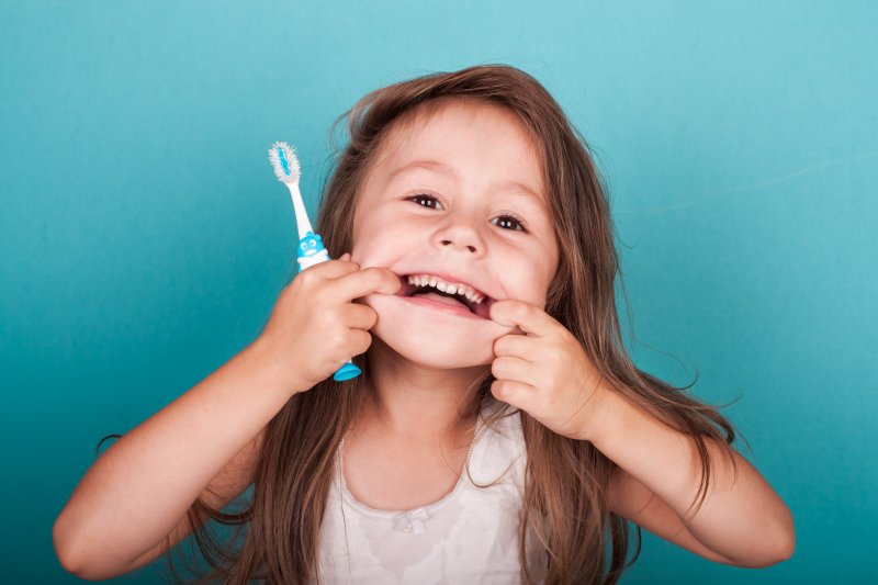 Cute little girl makes funny face with toothbrush