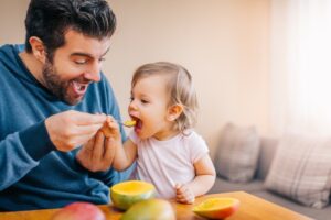 Dad feeding his child mangoes